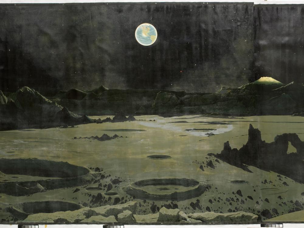 An imagining of what the moon's surface may look like. The Earth appears in the sky. 