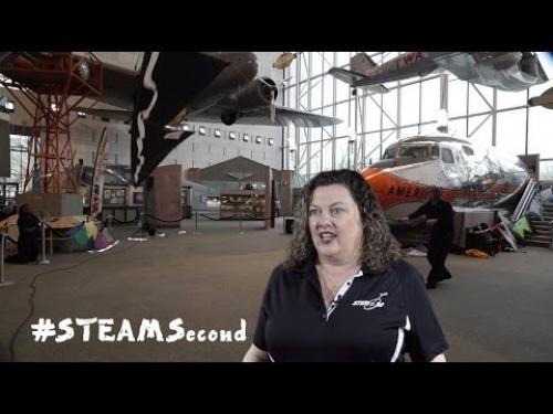 A person speaks about flying kites indoors at a Smithsonian event.