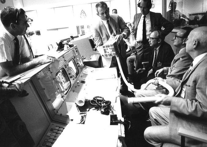 group of men around mission control desk
