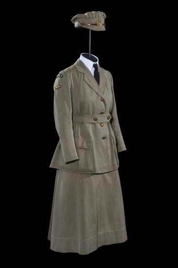 A women&#039;s military uniform comprised of a green wool coat with gold buttons and the WRAF insignia on the shoulders, and a matching green cap and skirt.